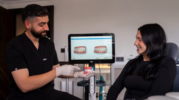A male dentist showing show dentures to a female patient