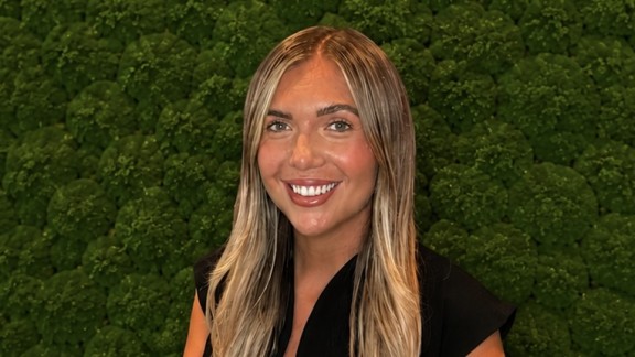 Woman smiling in front of shrubbery