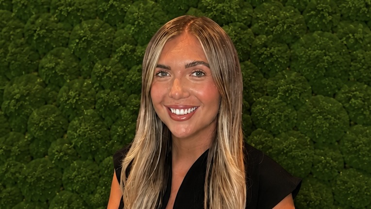 Woman smiling in front of shrubbery