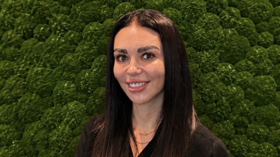 woman smiling in front of shrubbery