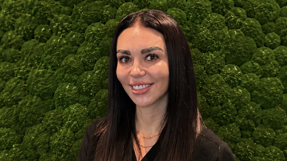 woman smiling in front of shrubbery