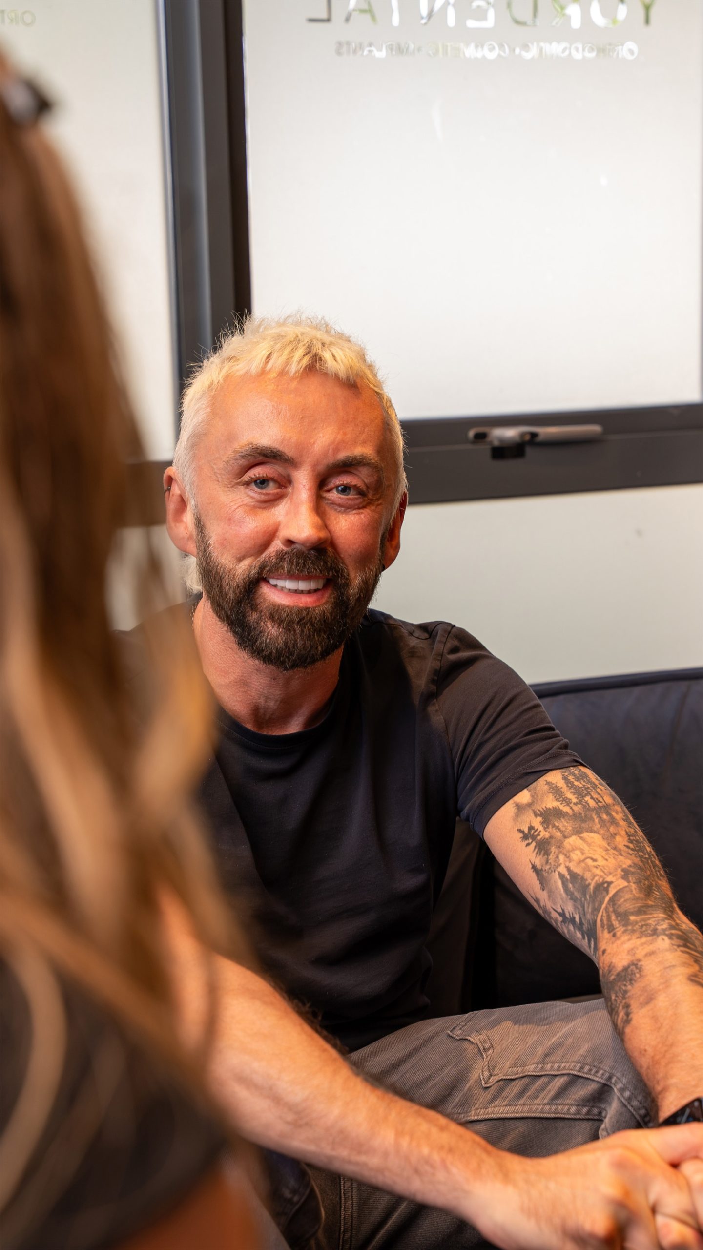 Man smiling whole talking to another person who is out of frame