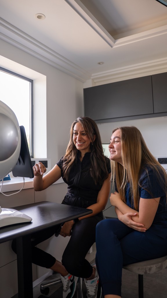 Deepa Vakil and a woman smile while looking at a screen